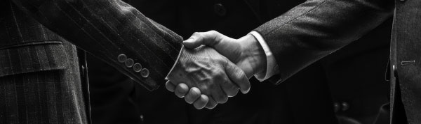 Luxury brand executives shaking hands at a wine and spirits marketing partnership meeting
